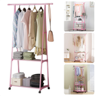 Pink metal clothing rack with shelves and wheels, displaying clothing and accessories in various room settings. Stylish and functional wardrobe solution.