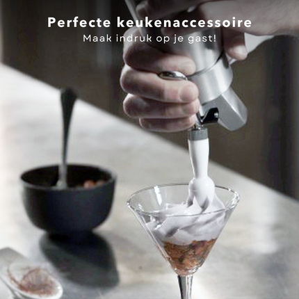 Hand using Cheqo Slagroomspuit to top a dessert with whipped cream in a glass, highlighting it as an ideal kitchen accessory.